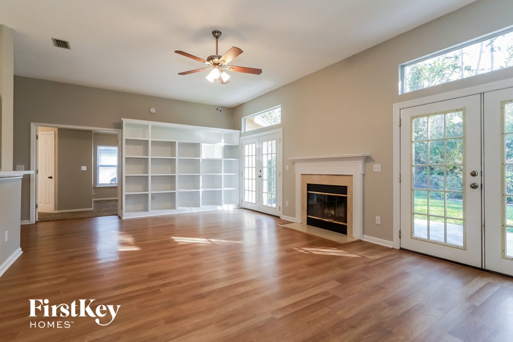 an empty living room with a fireplace and a ceiling fan