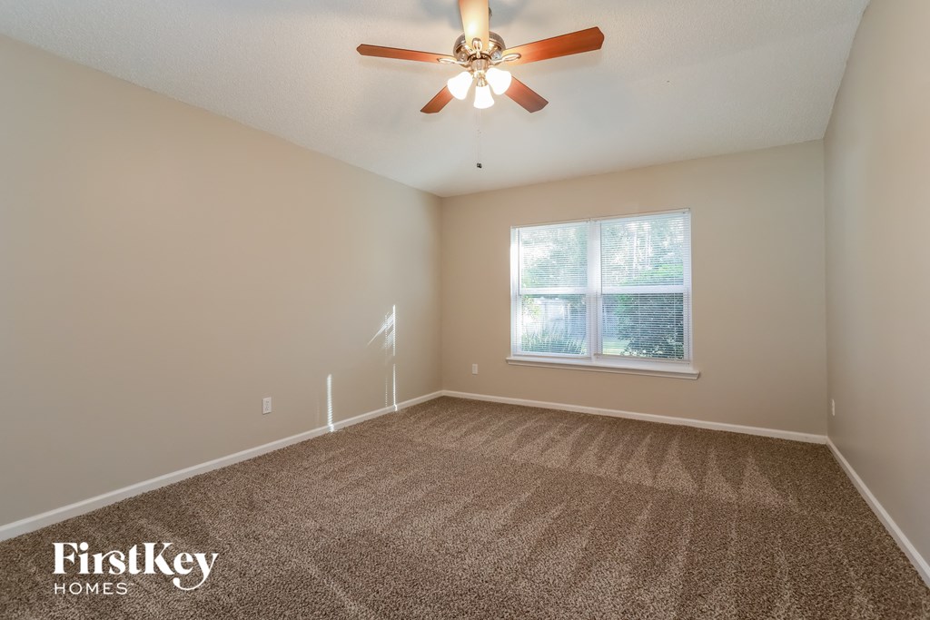 an empty room with a ceiling fan and a window