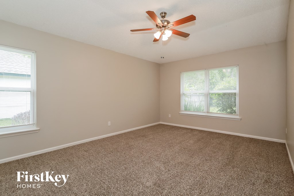 the master bedroom has a carpeted floor and a ceiling fan