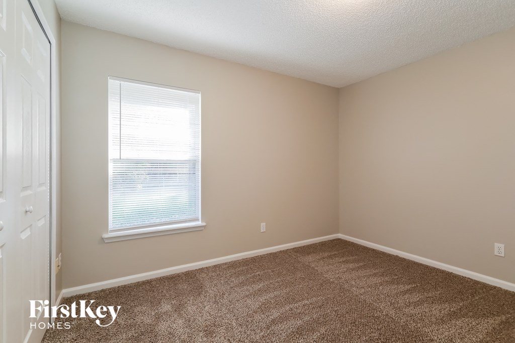 a bedroom with a carpeted floor and a window