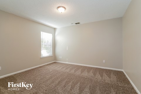 the spacious living room with carpet and a window