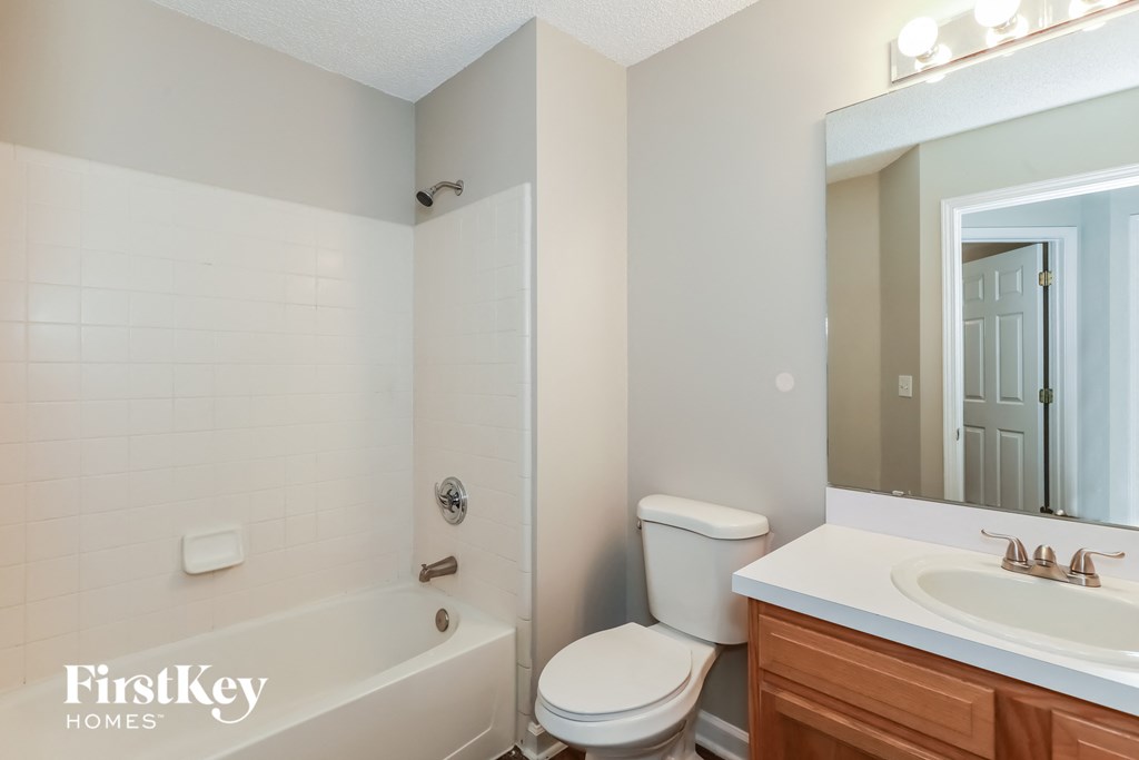 a bathroom with a toilet sink and tub and a mirror