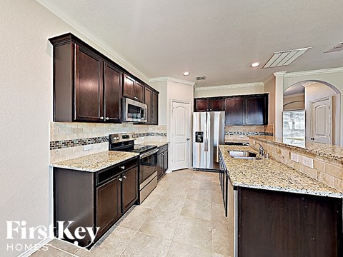 A kitchen with brown cabinets and a granite counter top.
