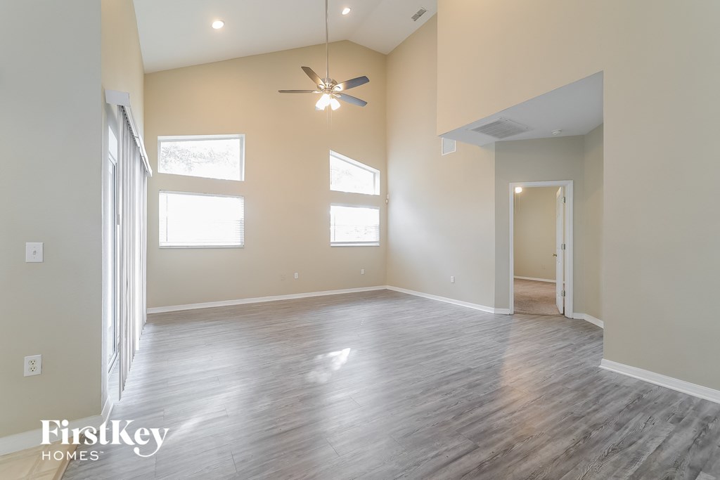 an empty living room with wood floors and a ceiling fan
