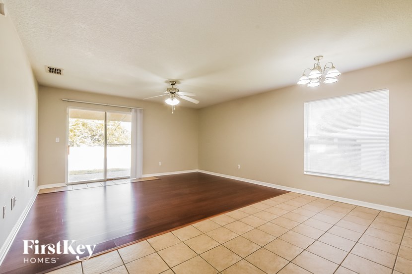 A spacious room with a ceiling fan and sliding glass doors leading to a patio.
