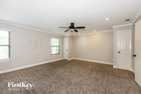 A spacious room with a ceiling fan and carpeted floor.