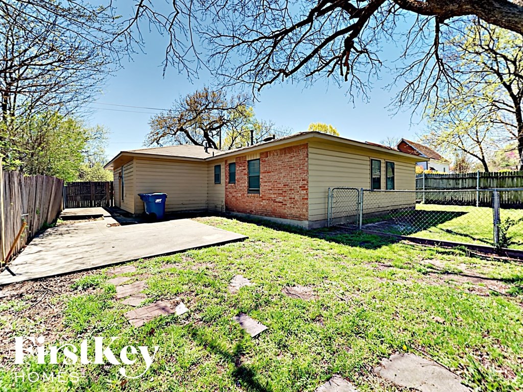 A house with a fence and a tree in front of it.