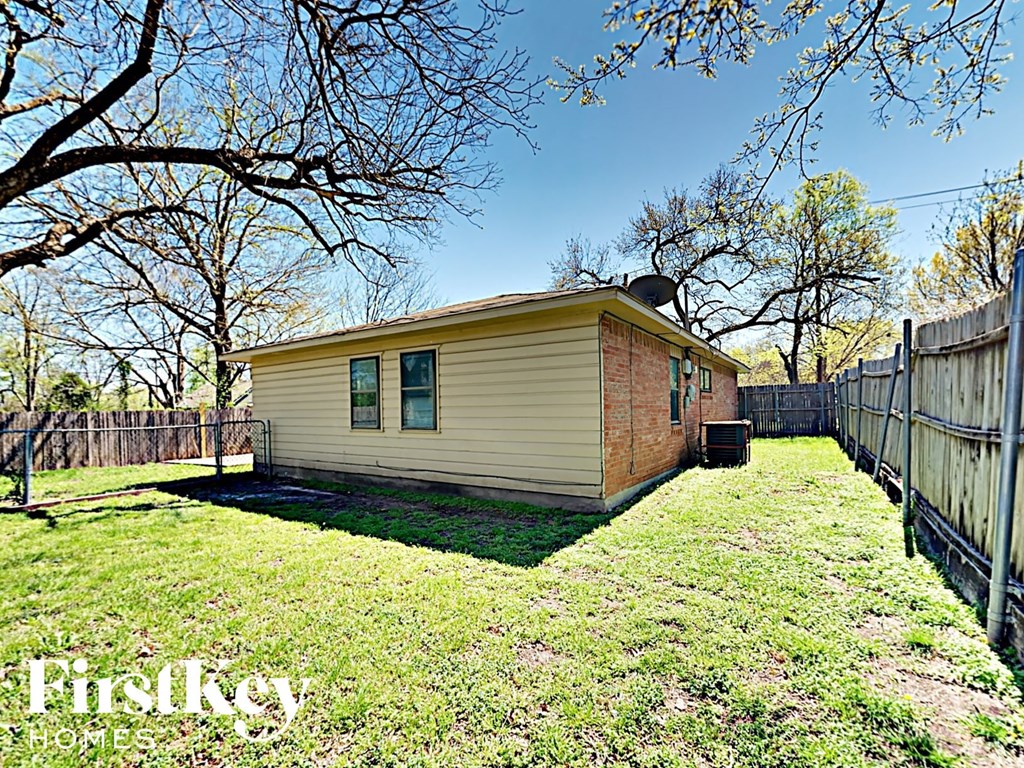 A small house with a fence and trees in the background.
