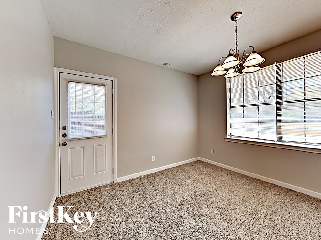 A room with a door, carpet, and a chandelier.