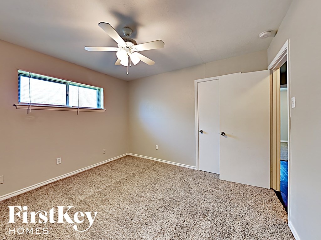 A room with a carpet floor, a ceiling fan, and a window with blinds.