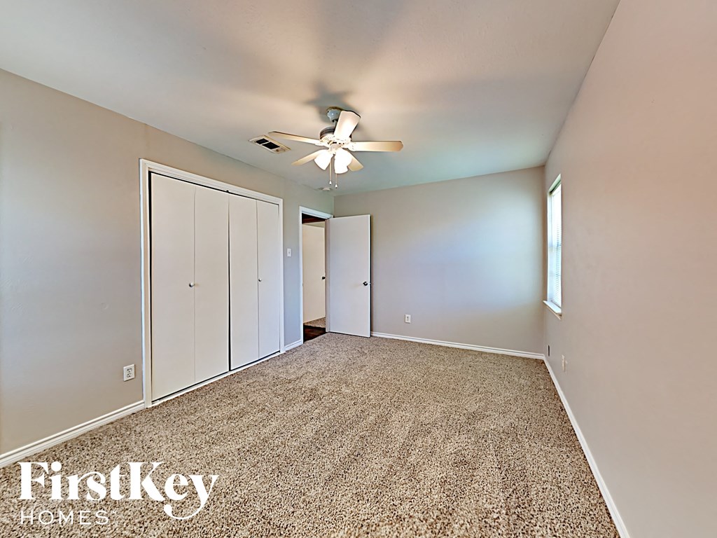 A room with a carpet floor and a ceiling fan.