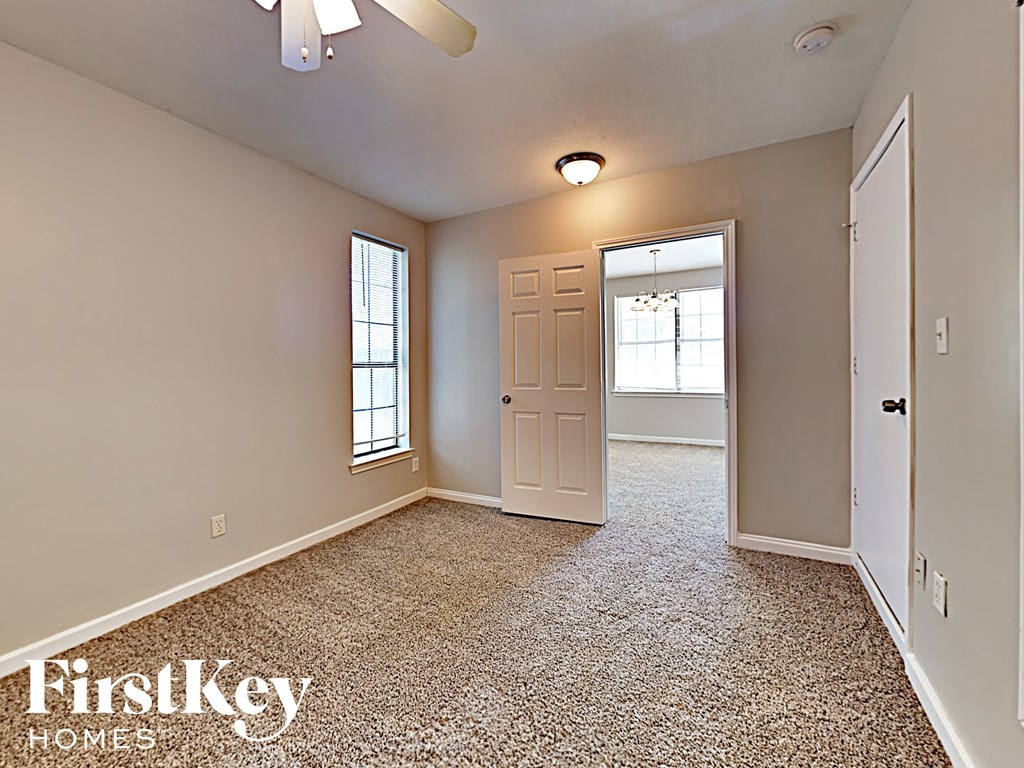 A room with a carpeted floor and a ceiling fan.
