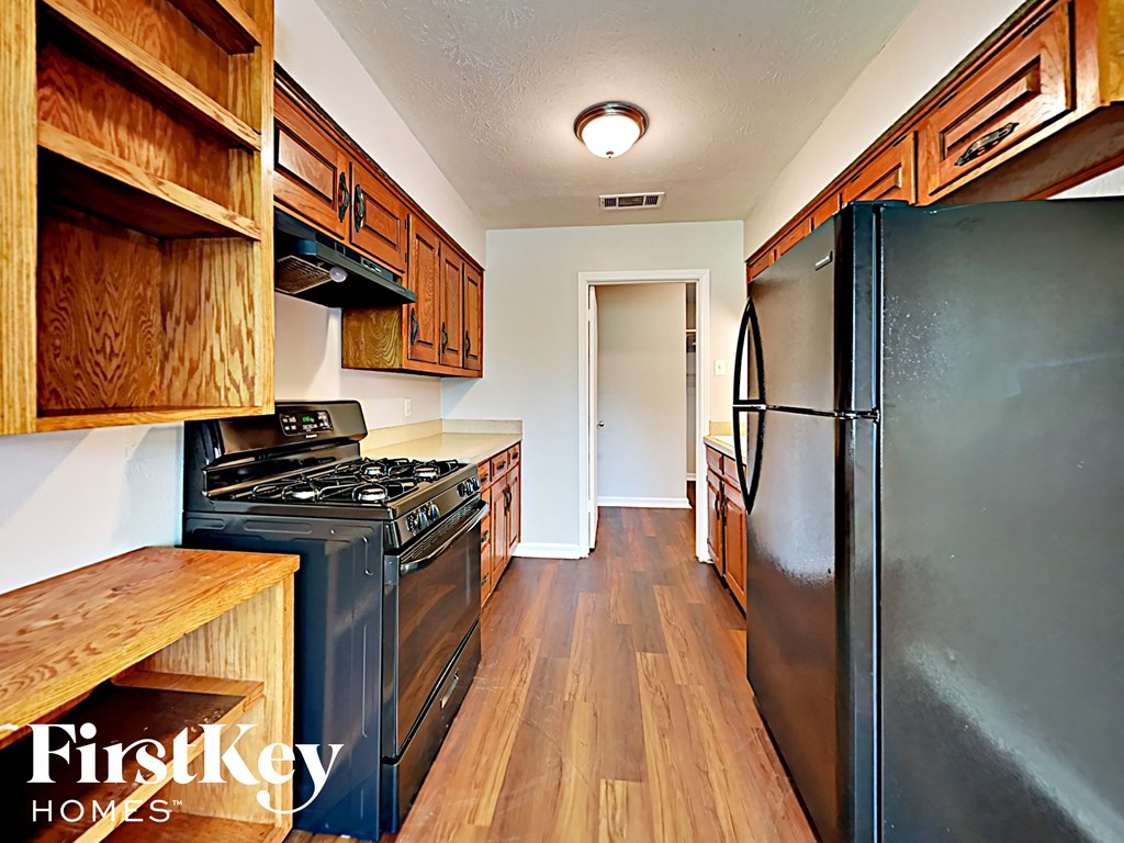 A kitchen with wooden cabinets and a black refrigerator.