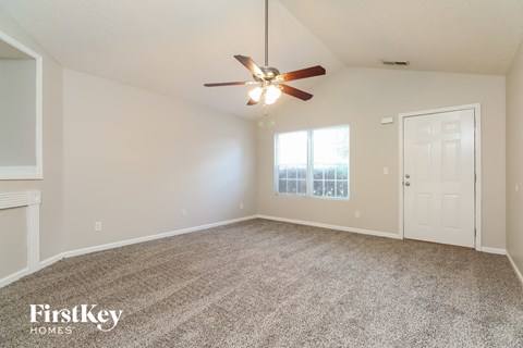A spacious room with a ceiling fan and a door leading to another room.