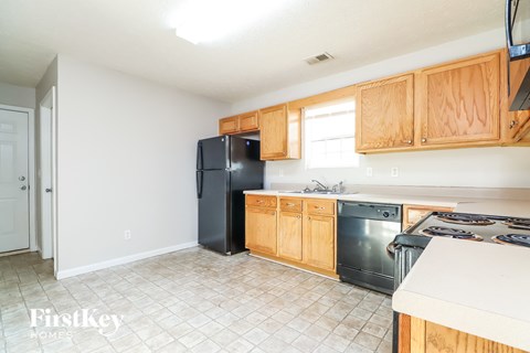 A kitchen with wooden cabinets and a black fridge.