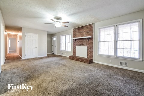 A spacious room with a brick fireplace and a ceiling fan.