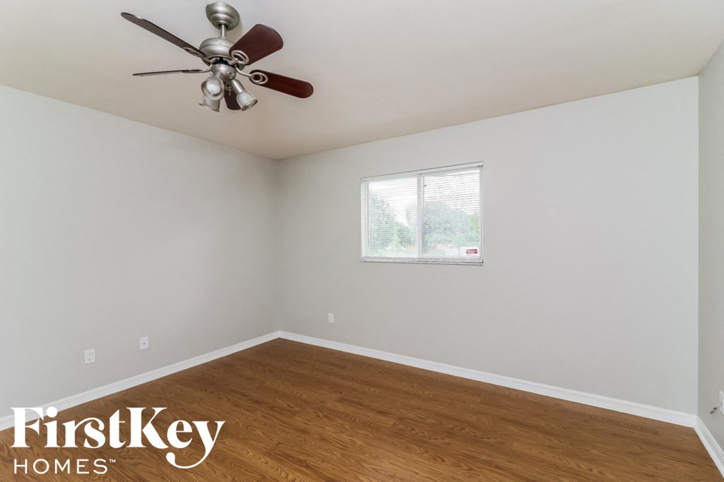 a bedroom with wood floors and a ceiling fan