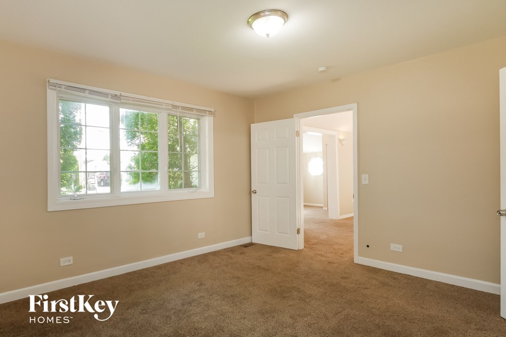 a bedroom with a carpeted floor and a white door and window