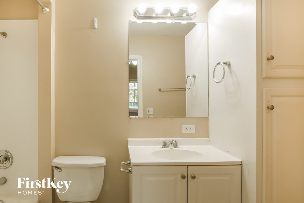 a bathroom with a toilet sink and mirror and a mirror above a sink and toilet