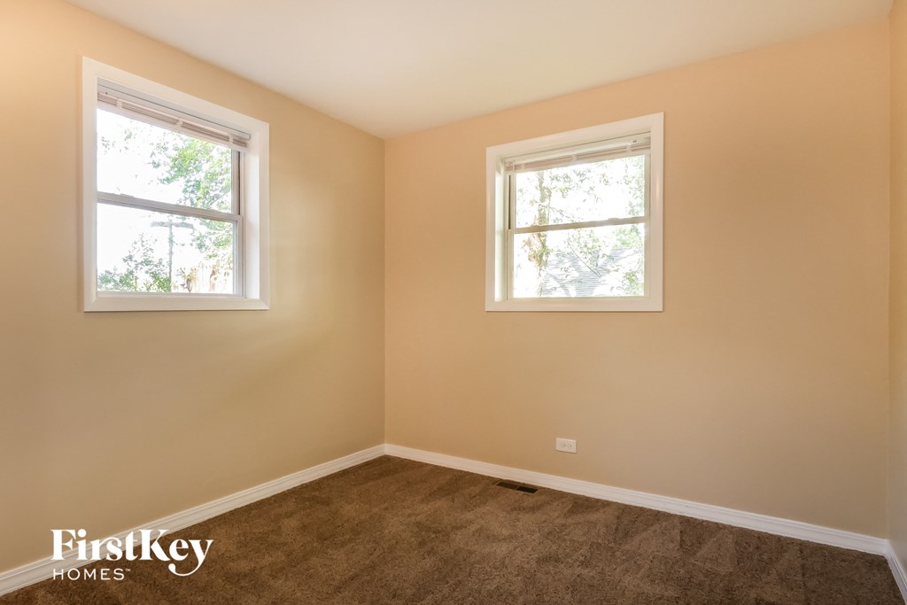 a bedroom with two windows and a carpeted floor
