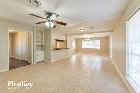 A spacious living room with a ceiling fan and tiled flooring.