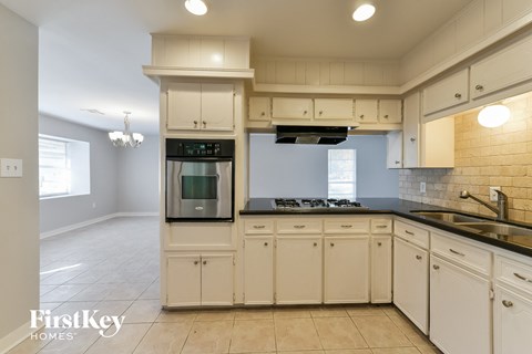 A kitchen with white cabinets and a black countertop.