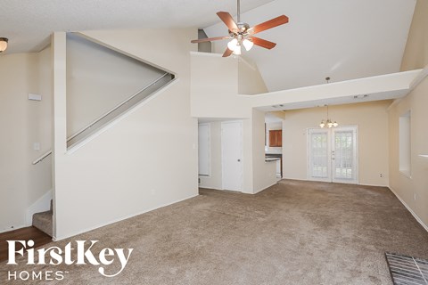 A spacious living room with a ceiling fan and a carpeted floor.