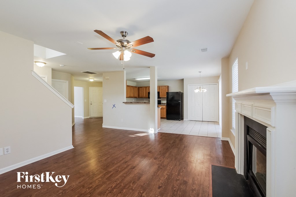 an empty living room with a fireplace and a ceiling fan