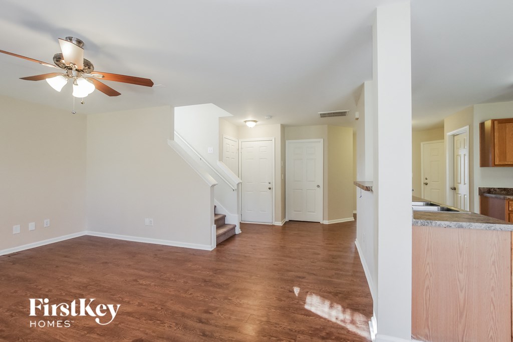 an empty living room with a ceiling fan and a kitchen