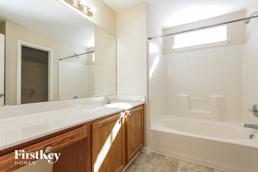 a bathroom with a white tub and a sink and a mirror