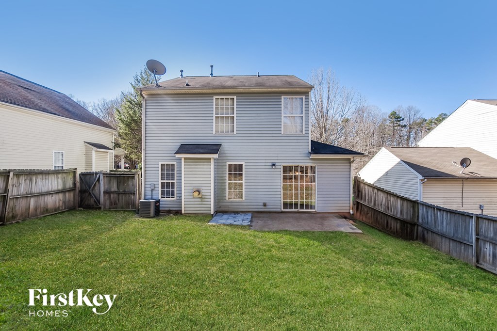 a backyard with a white house and a fence