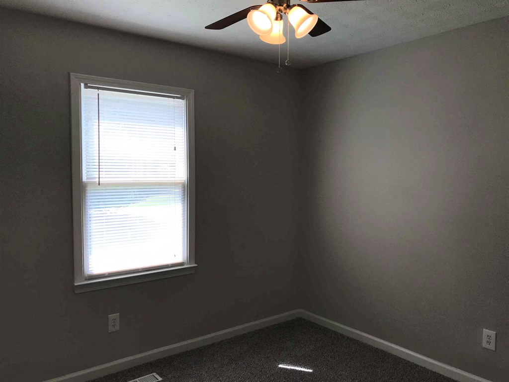 an empty room with a window and a ceiling fan