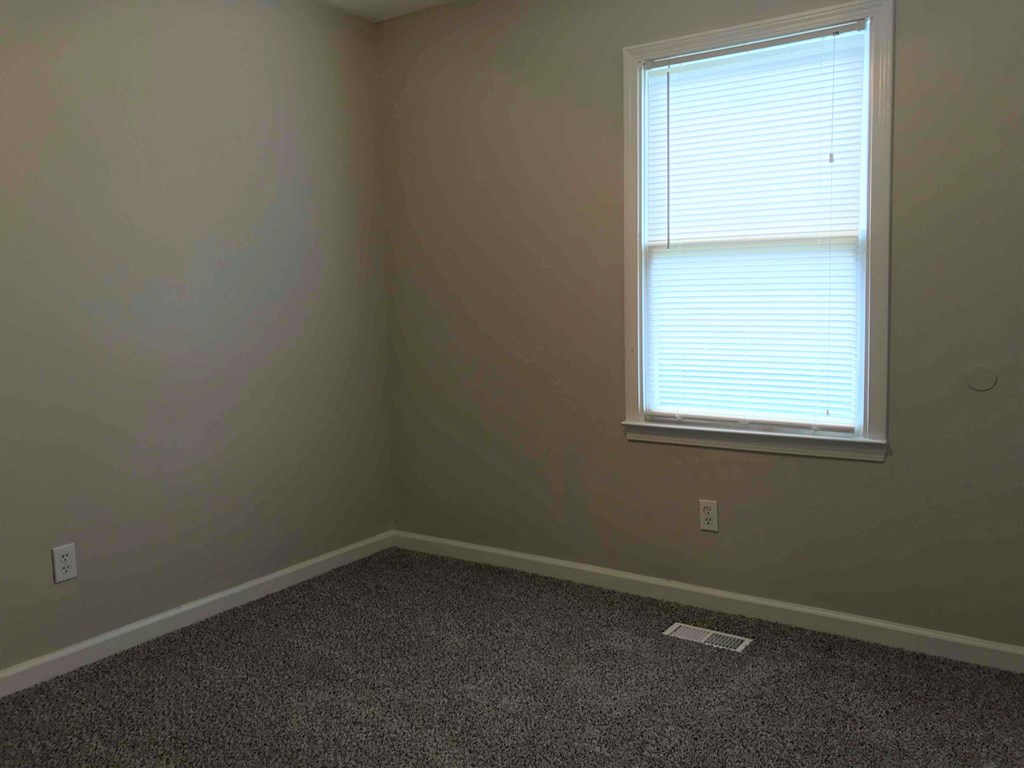 a small room with a window and a carpet