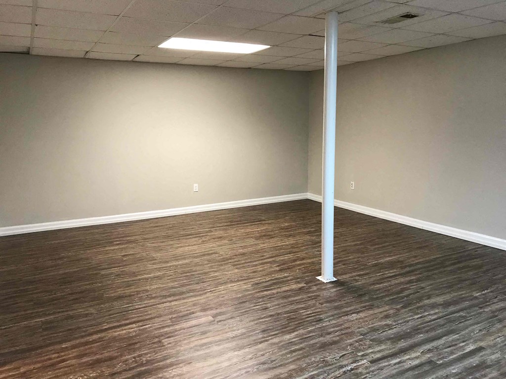 an empty room with wood flooring and a white wall