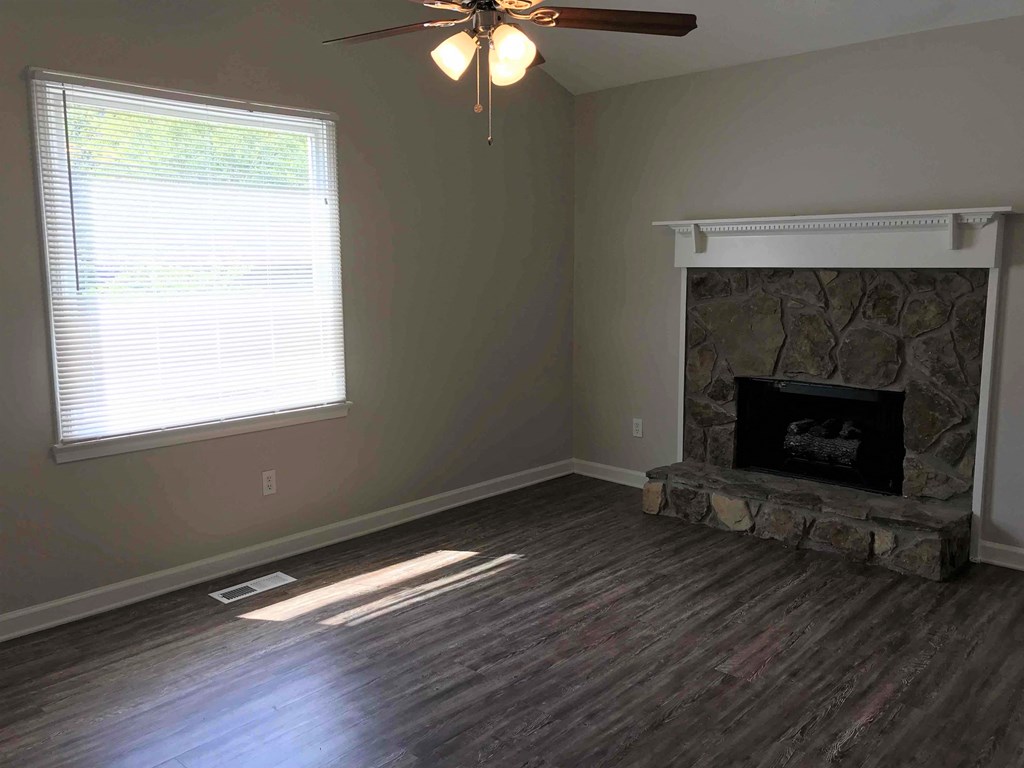 a living room with a fireplace and a ceiling fan