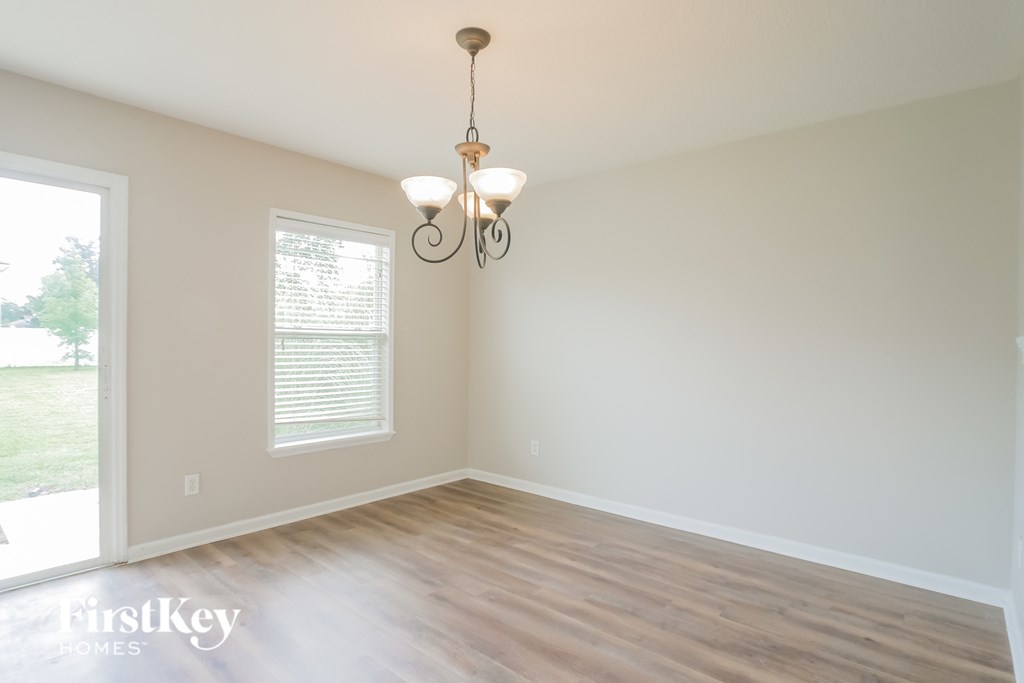 an empty living room with a wooden floor and a chandelier