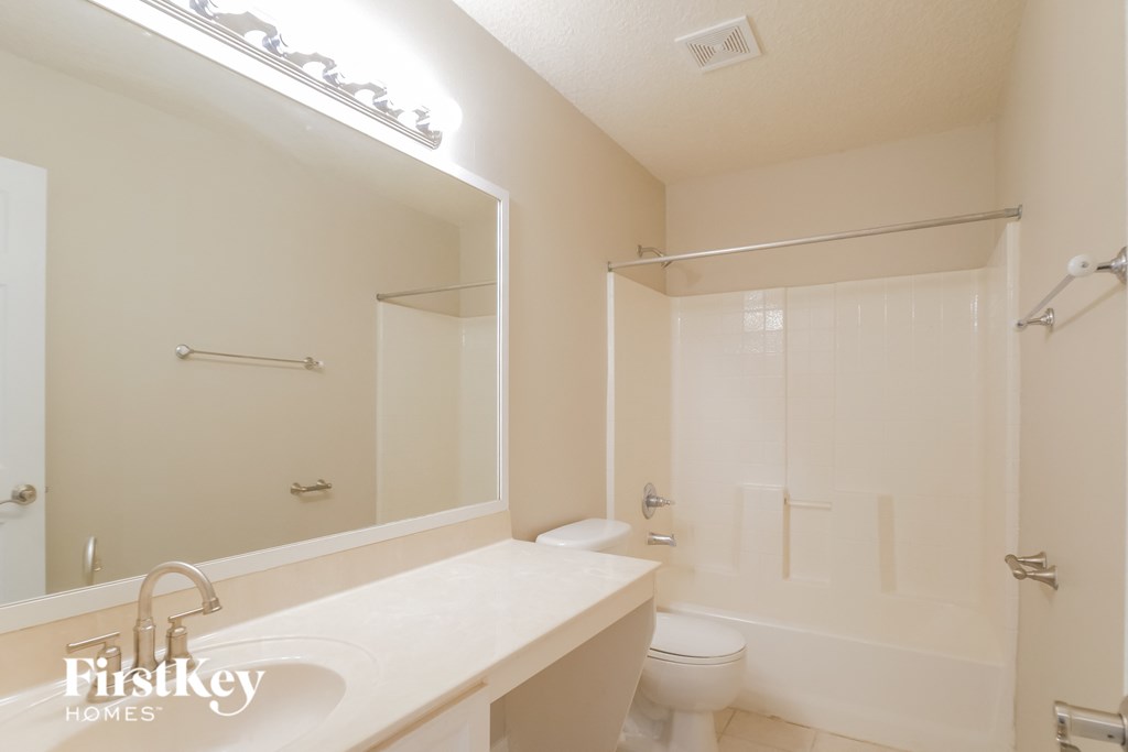 a white bathroom with a large mirror and a white toilet