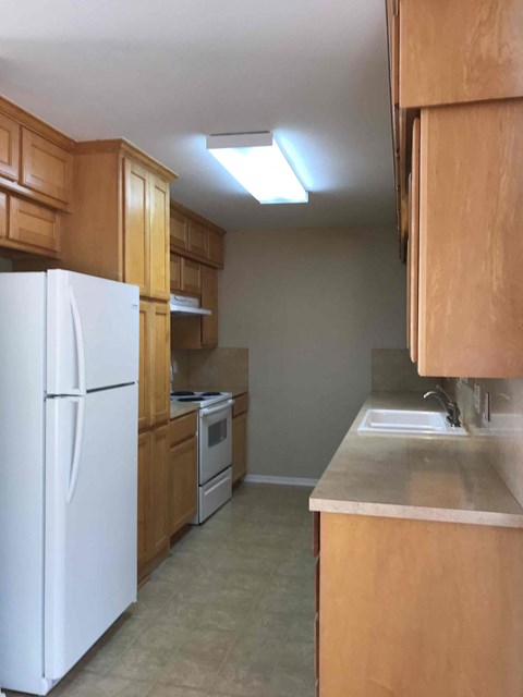 A kitchen with a white refrigerator and wooden cabinets.