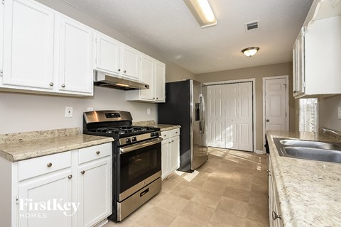 A kitchen with white cabinets and a black refrigerator.