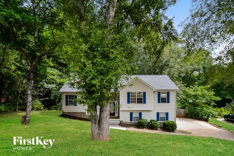 a white house with blue shutters and a yard with trees