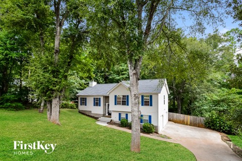 a white house with blue shutters and trees