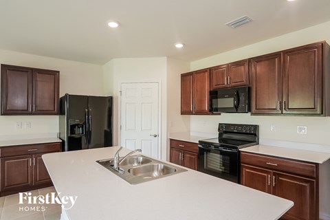 A kitchen with brown cabinets and a black fridge.
