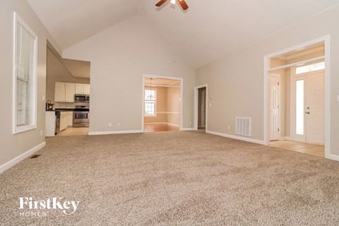 A spacious living room with a carpeted floor and a ceiling fan.