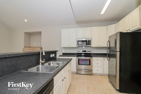 A kitchen with a black refrigerator and a stove top oven.