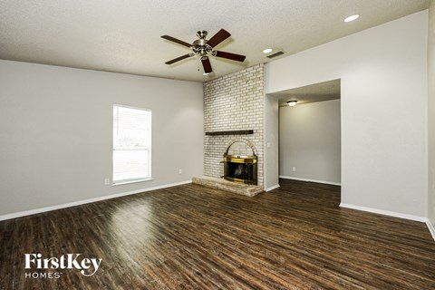 A room with a fireplace and a fan on the ceiling.