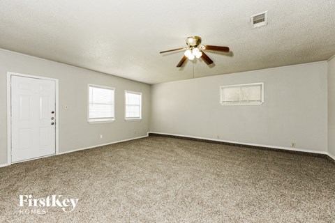 A spacious room with a ceiling fan and two windows.