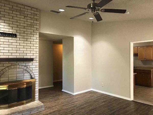 A living room with a fireplace and a ceiling fan.