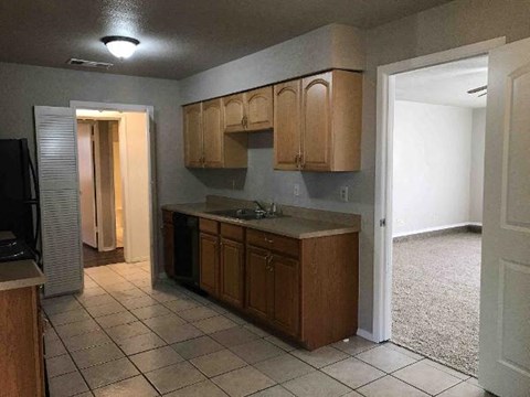 A kitchen with wooden cabinets and a black fridge.