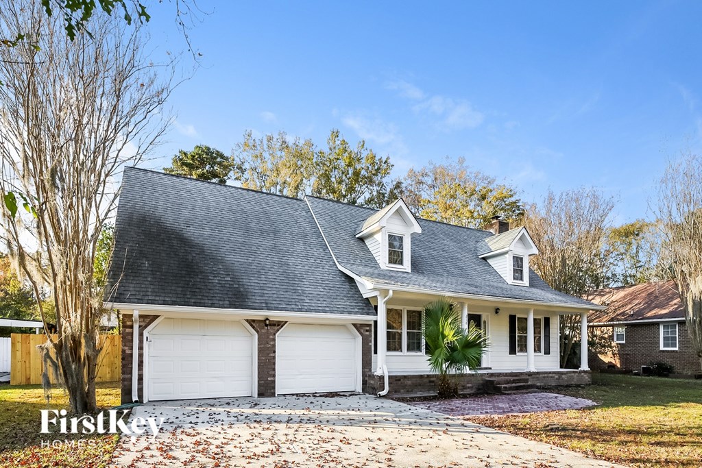 A house with a grey roof and white garage doors is for sale.