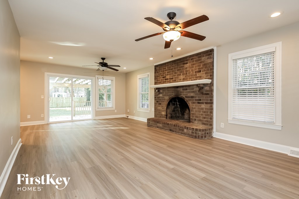 A spacious room with a brick fireplace and a ceiling fan.